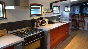 Een moderne keuken met een gasfornuis, oven en een koffiezetapparaat op het aanrecht.
