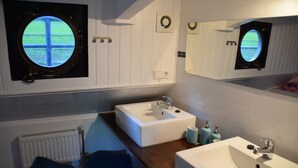 Een badkamer met twee wasbakken, een spiegel, een raam met uitzicht en een handdoekrek.