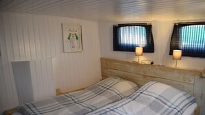 Een eenpersoonsbed met een houten hoofdbord en twee bedlampen.