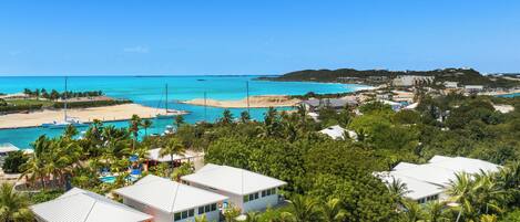 Um resort costeiro com vários edifícios brancos, uma praia e águas azuis cristalinas.