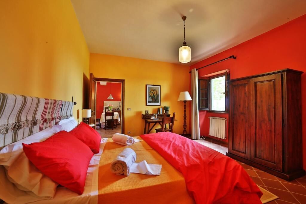 A hotel room with two beds, a wooden wardrobe, a dining table with chairs, and a view of the dining area.