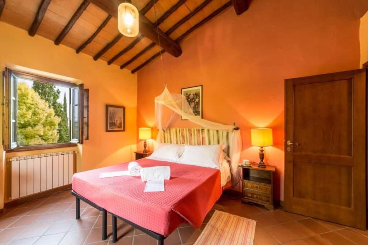 Une chambre à coucher avec un lit, des lampes de chevet, une fenêtre et une porte.