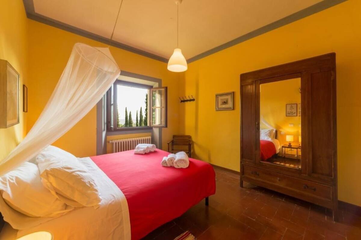 Une chambre d’hôtel avec un lit, une fenêtre, un miroir et une porte.