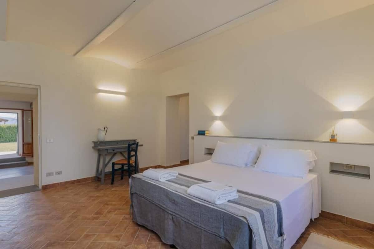 Une chambre à coucher comprenant un lit, des tables de chevet, un bureau et une chaise.