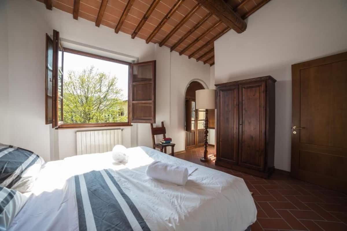 Une chambre à coucher avec un lit, une fenêtre, une armoire et une lampe.