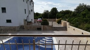A rooftop swimming pool with a stone wall and a white building in the background. - Apartment in Vinišće with Balcony, Air condition, WIFI, Washing machine (4753-4) (Vinišce)