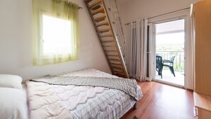 A bedroom with a bed, a window with sheer curtains, a wooden ladder, and a sliding glass door leading to an outdoor area with chairs. - Apartment in Vinišće with Balcony, Air condition, WIFI, Washing machine (4753-4) (Vinišce)