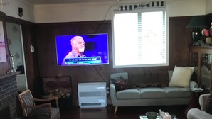 A living room with a television, sofa, armchair, and a coffee table. - Rob's Beach House Riverton (Riverton)