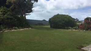 A grassy yard with trees and a fence. - Rob's Beach House Riverton (Riverton)