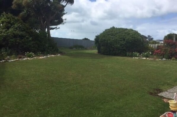 A grassy yard with trees and a fence.