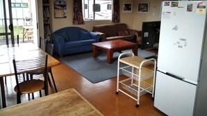 Un espacio habitable compacto con kitchenette, comedor con mesa y sillas, sofá y refrigerador.