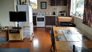 Una cocina compacta con refrigerador, estufa, microondas y comedor con mesa y sillas.