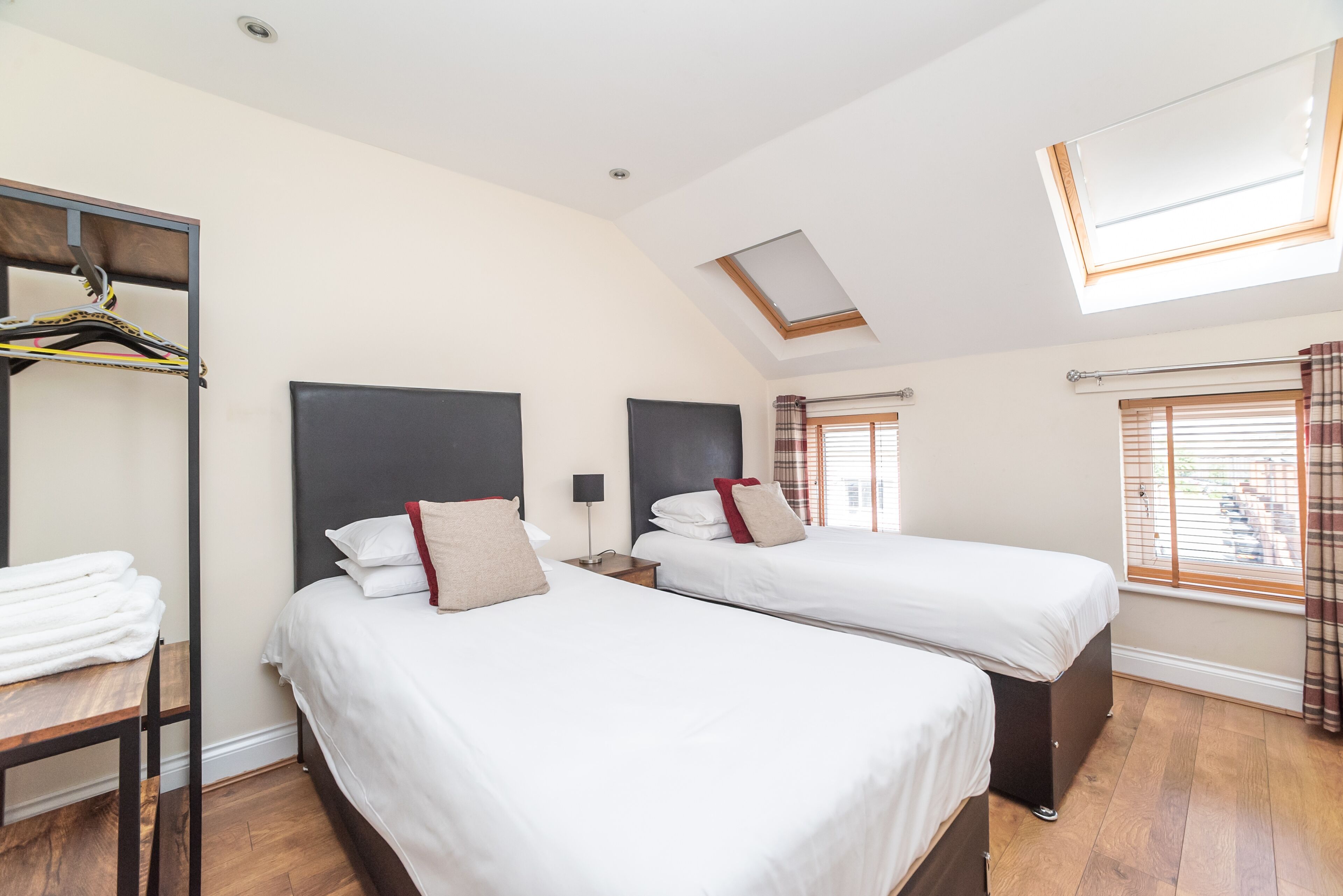 Quarto de hotel com duas camas, um guarda-roupa, um claraboia e uma janela com cortinas.