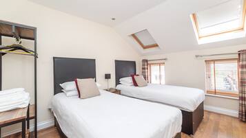 Quarto de hotel com duas camas, um guarda-roupa, um claraboia e uma janela com cortinas.