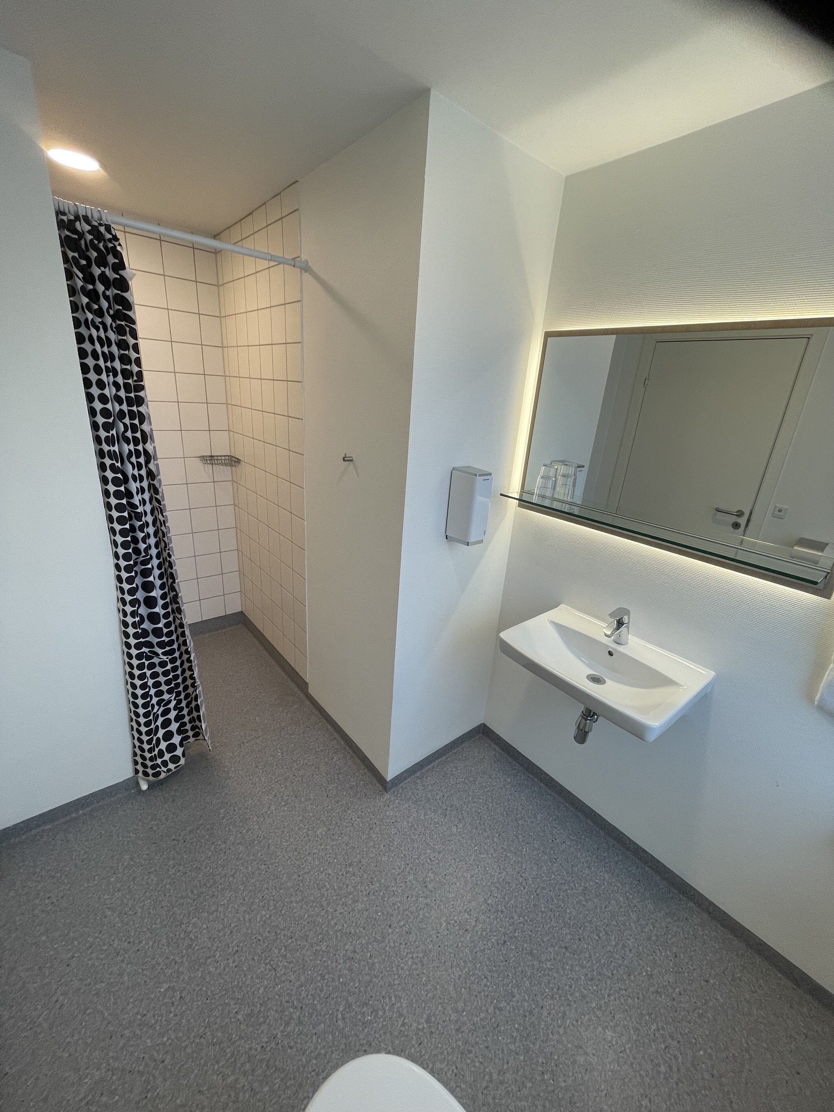 Un baño moderno con ducha, lavamanos y espejo.