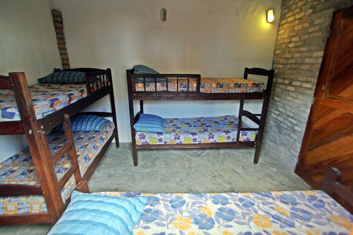 Ein Schlafsaalzimmer mit Stockbetten, einer Ziegelwand und einer Holztür.