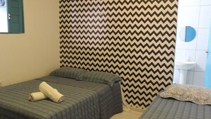 Ein Zimmer mit zwei Betten, einer strukturierten Wand, einem Waschbecken und einem Spiegel.