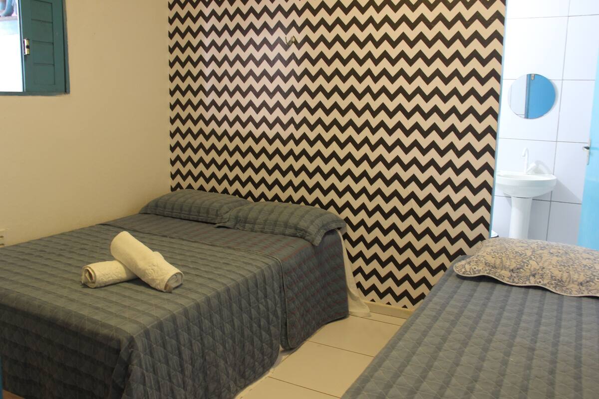 Ein Zimmer mit zwei Betten, einer strukturierten Wand, einem Waschbecken und einem Spiegel.