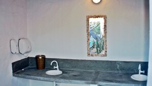 Ein Badezimmer mit zwei Waschbecken, einem Spiegel und einer Wandleuchte.
