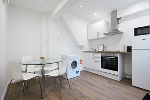 A modern kitchen with a washing machine, oven, and microwave.