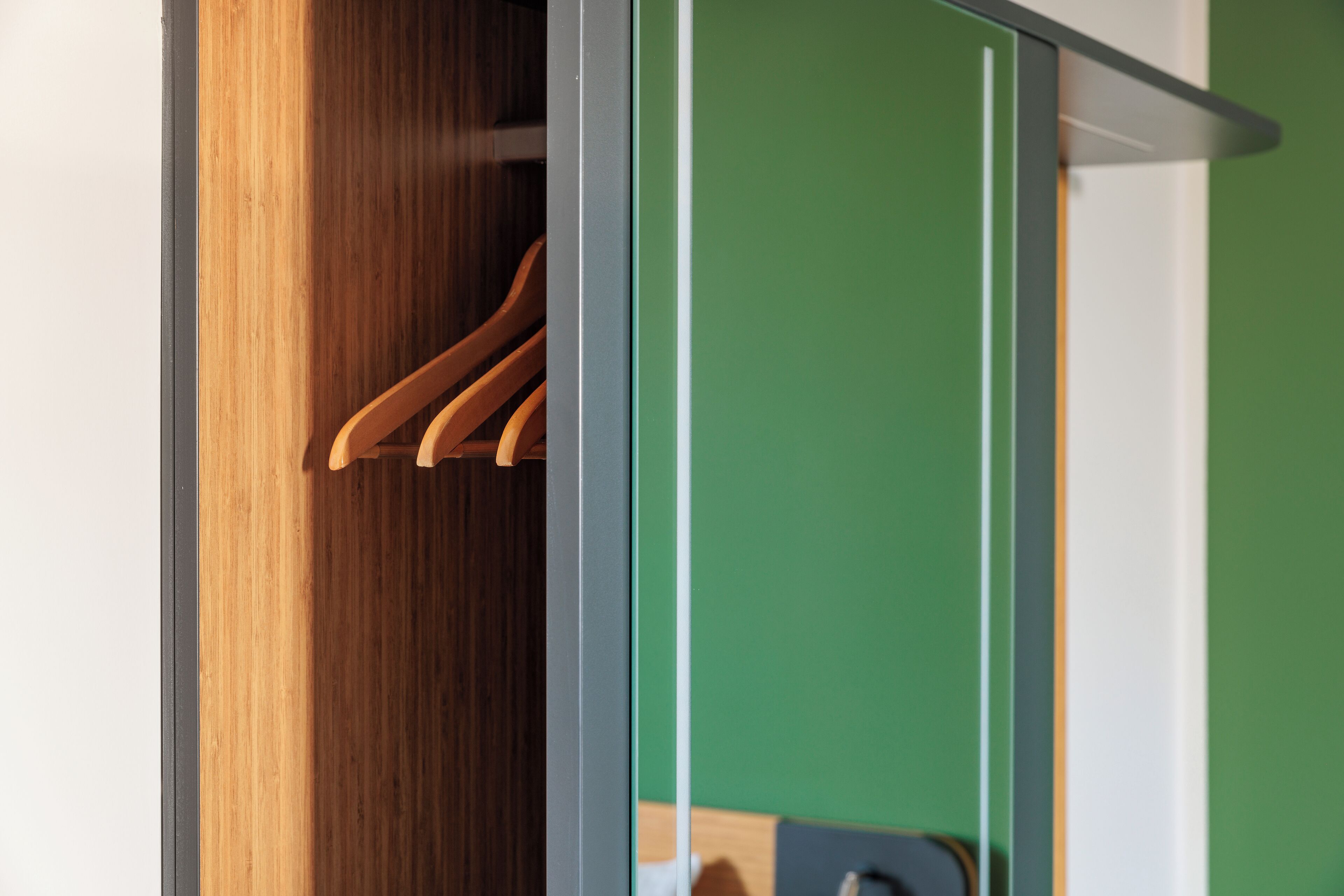 Un armario de madera con espejo y pared verde.