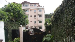A gated entrance with a sign reading "GOLD COURT" leading to a multi-story building with balconies and air conditioning units. - Gold Court Appartements Meublés (Yaoundé)
