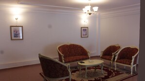 A room with three armchairs, a small round table, and a patterned rug. - Gold Court Appartements Meublés (Yaoundé)