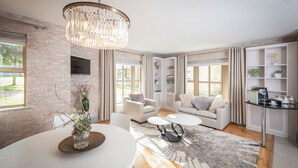 A modern living room with a chandelier, white sofas, a coffee table, and a bookshelf. - Brennan Court Guest Accommodation (Limerick)