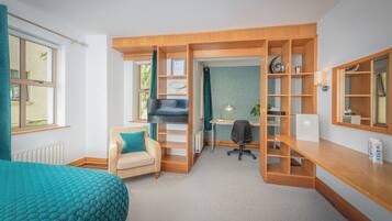 Una habitación pequeña con cama, escritorio, silla y estanterías empotradas.