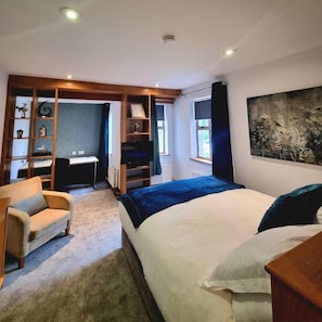Un dormitorio con una cama, un escritorio y una silla. Hay una estantería y un cuadro en la pared.