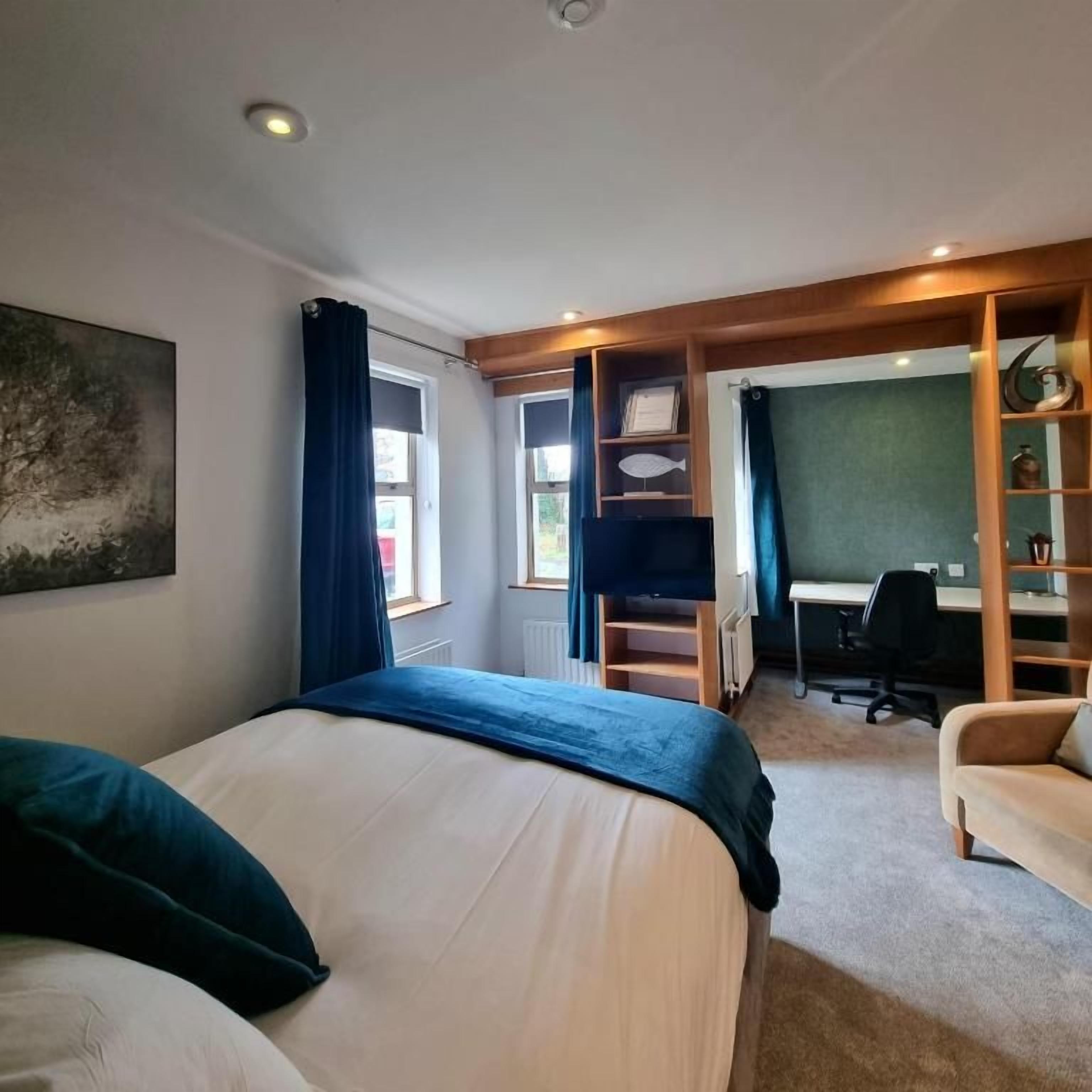 Un dormitorio con una cama, un escritorio, una silla y una estantería.