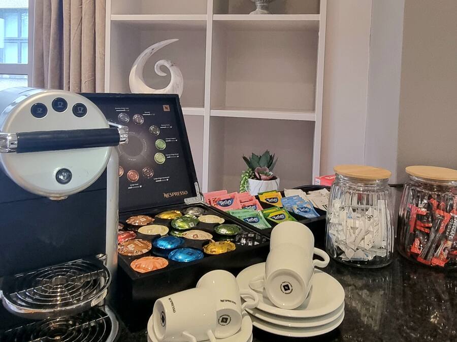 A coffee station with a Nespresso machine, a selection of coffee pods, and a small potted plant.