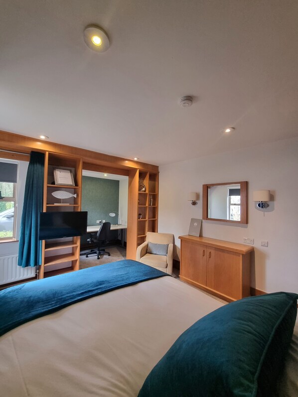 A hotel room with a bed, a desk, a chair, a bookshelf, and a mirror. - Brennan Court Guest Accommodation (Limerick)