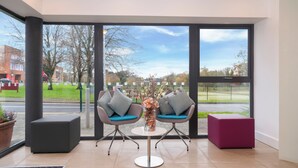 A modern interior with two grey chairs with blue cushions, a round table, and a vase of flowers. - Brennan Court Guest Accommodation (Limerick)