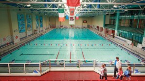 An indoor swimming pool with lanes, a diving platform, and a spectator area with red seats. - Brennan Court Guest Accommodation (Limerick)