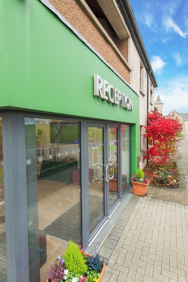 A reception area with a green facade, large glass windows, and potted plants outside. - Brennan Court Guest Accommodation (Limerick)