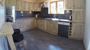 Una cocina moderna con armarios de madera, horno empotrado, lavavajillas y ventana que proporciona luz natural.