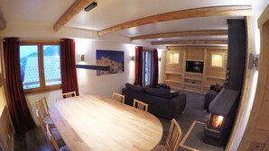 Una sala de estar acogedora con chimenea, un comedor con mesa y sillas de madera, y un televisor al fondo.