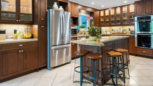 A modern kitchen with wooden cabinets, stainless steel appliances, and a central island with stools. - Modern Tropical Oasis, Private Heated Pool, Near Beaches! (Wilton Manors)