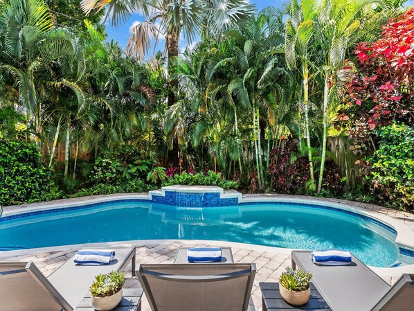 A swimming pool surrounded by lush tropical vegetation.