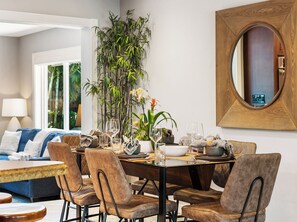 A dining area with a wooden dining table, brown upholstered chairs, and a large potted plant.
