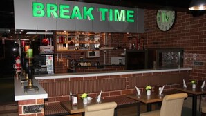 Un restaurante con pared de ladrillo, un reloj y una zona de bar con taburetes y mostrador.