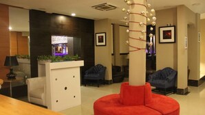 Un moderno vestíbulo con mostrador de recepción, zona de estar y una columna decorativa.