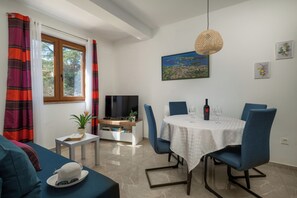 Un salon moderne comprenant un canapé, une table à manger avec des chaises, un téléviseur et une fenêtre avec des rideaux.