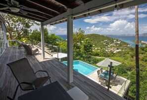 A covered outdoor area with a pool, seating, and a view of a coastal landscape. - Amazing views,6 bdrm, private pool-Cruz Bay - Whole house generator (St. John)