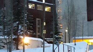 A snow-covered outdoor staircase leading to a building with multiple windows and a modern architectural design. - Upscale Indian Themed PENTHOUSE On Ski Access Level! Vaulted ceiling. High rated (Winter Park)