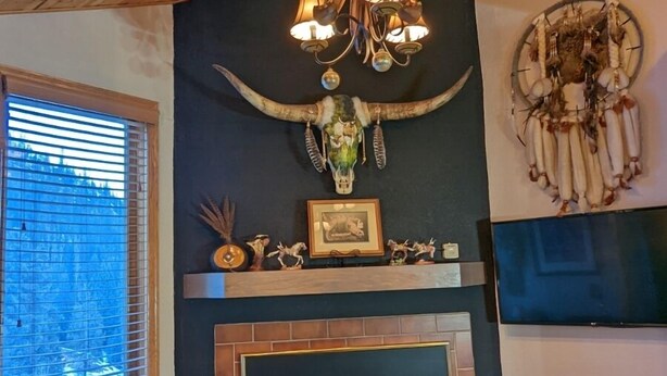A cozy living room with a fireplace, a chandelier, and rustic decor. - Upscale Indian Themed PENTHOUSE On Ski Access Level! Vaulted ceiling. High rated (Winter Park)