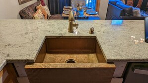 A kitchen with a granite countertop, a stainless steel sink, and a wooden drawer. - Upscale Indian Themed PENTHOUSE On Ski Access Level! Vaulted ceiling. High rated (Winter Park)