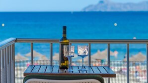 Une table avec une bouteille et des verres sur un balcon donnant sur la mer.