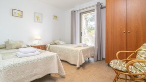 Une chambre avec deux lits, une armoire en bois et une chaise en osier.